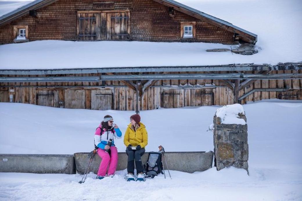 Snowshoe hiking in Schönhalden: two women relax in the winter mountain landscape.