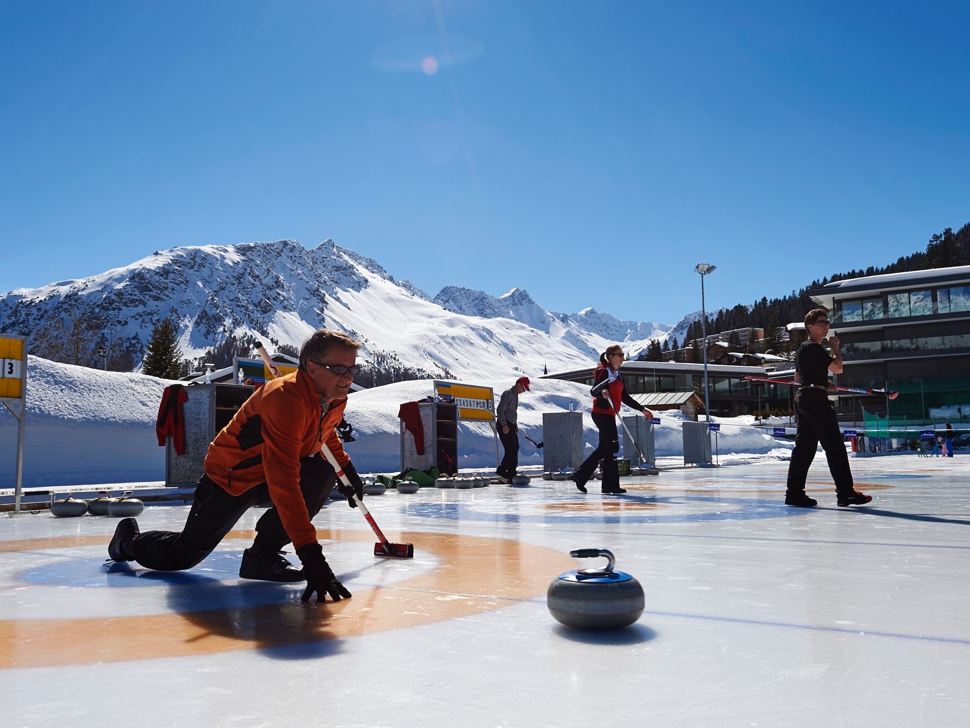 Szkolenie w curlingu w Arosie dla początkujących na lodowisku w słoneczny dzień.