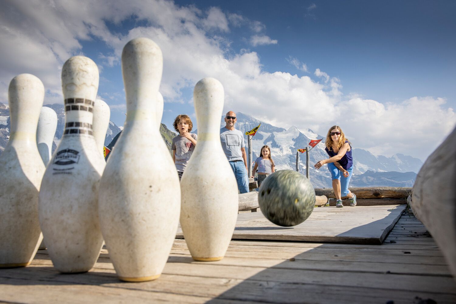 Sennenspielplatz: Kinder spielen Bowling im Freien, umgeben von Bergen und schöner Landschaft.