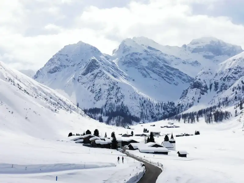 डावोस में Sertigtal की स्कीइंग यात्रा, बर्फ से ढके पहाड़, साफ सुथरी सर्दियों का दृश्य।