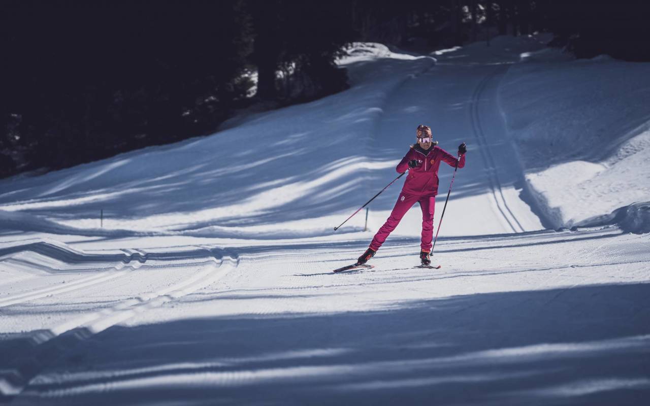 Cours privé de ski de fond en skating à Davos. Skieuse en vêtements roses sur une piste enneigée.