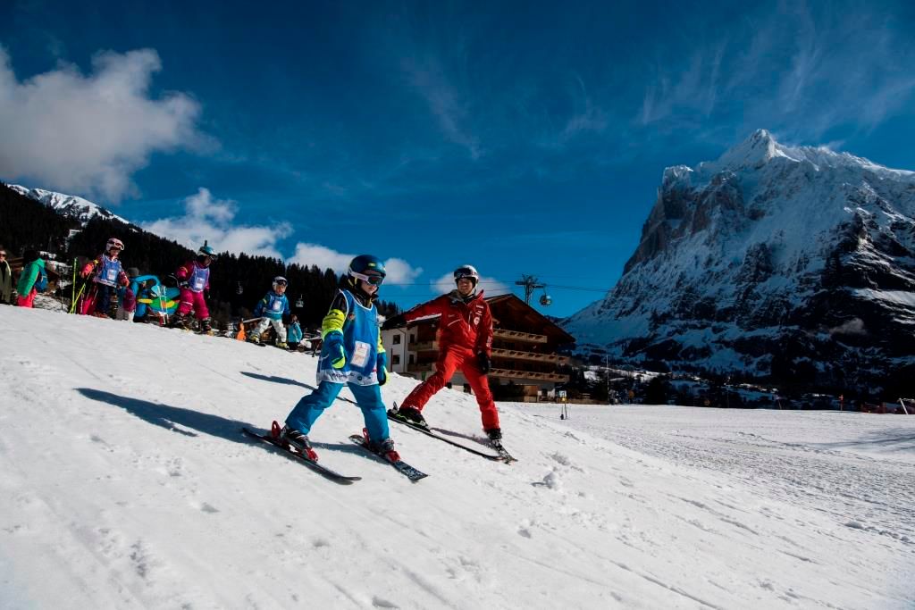Gruppenunterricht Ski Kinder Lehrer in den Bergen über natuerliche Winterlandschaft.