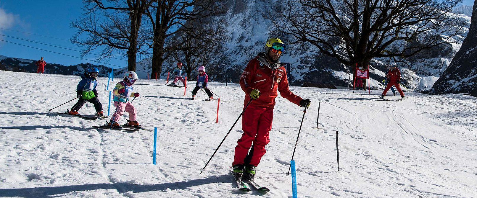 Gruppenunterricht Ski Kinder Slalom beim Skifahren im Winter mit viel Spass und Teamarbeit.