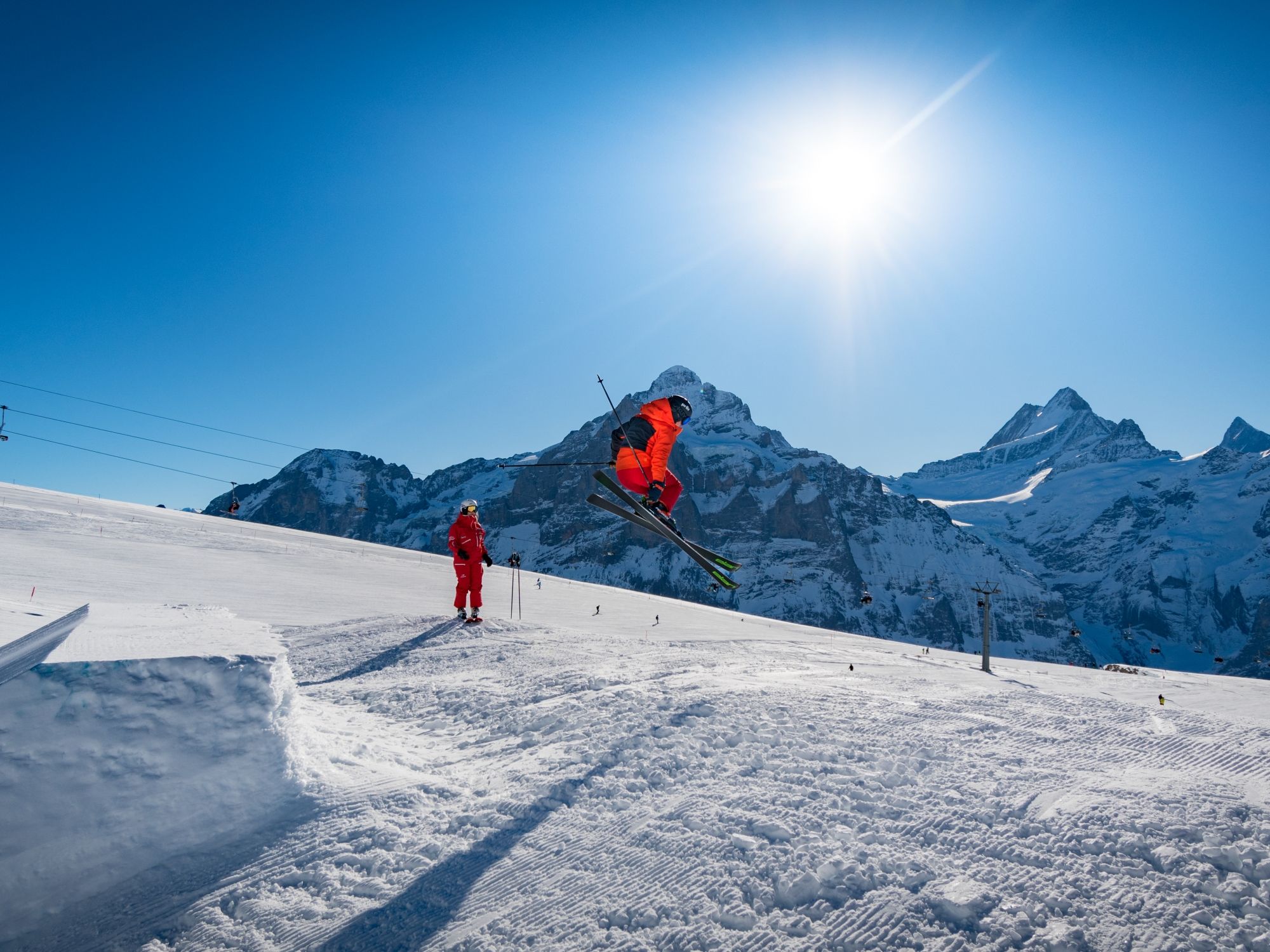 Freestyle cursus Grindelwald met een Skier in de lucht boven een sneeuwpiste.