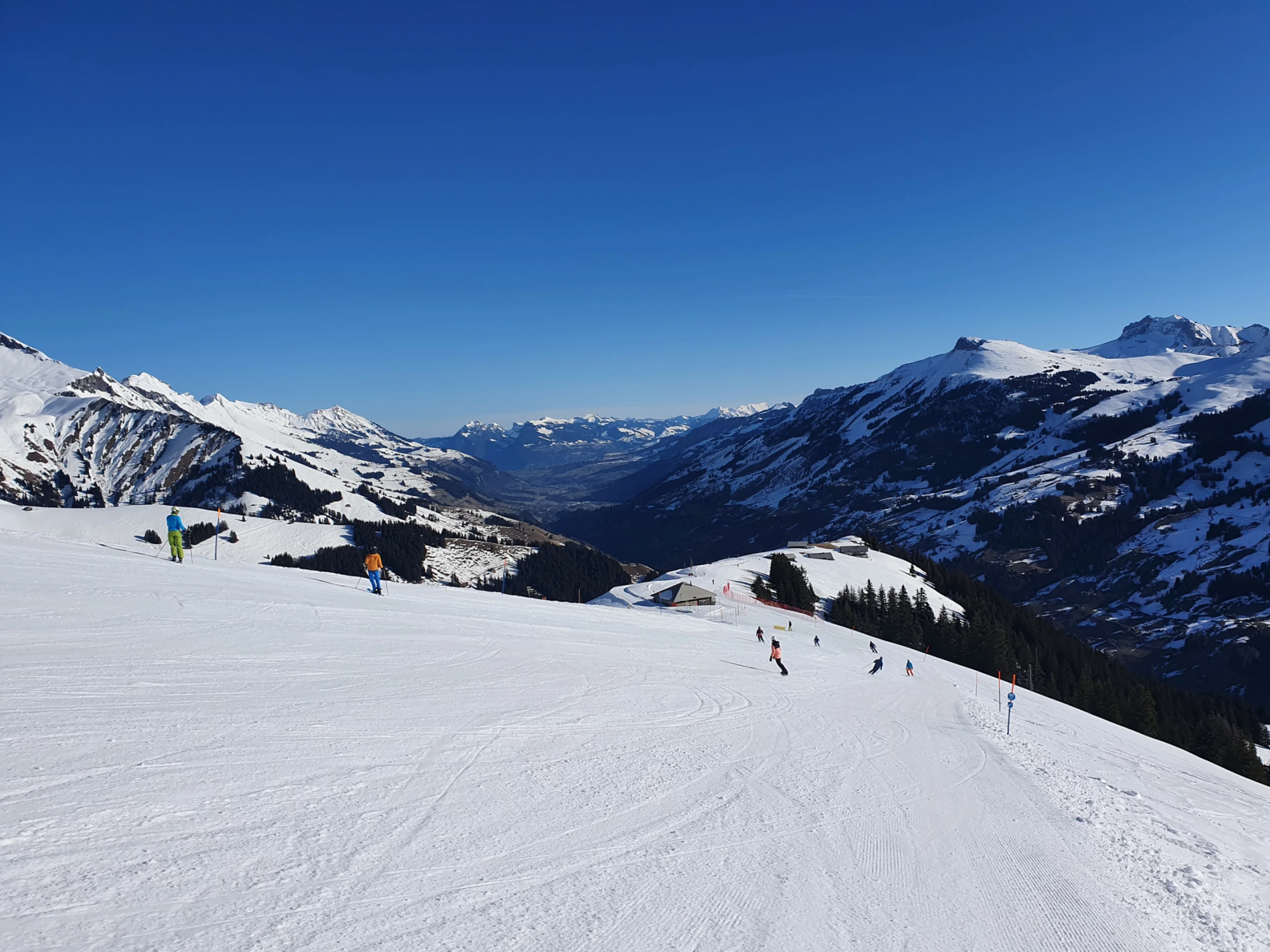 เล่นสกีที่อาเดลโบเดิน ทชิเนนทัลป์ กับภูเขาที่ปกคลุมด้วยหิมะและท้องฟ้าสีฟ้า.