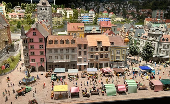 Miniaturstadt: Belebter Markt mit bunten Ständen und fröhlichen Menschen in Sonnenstadt.