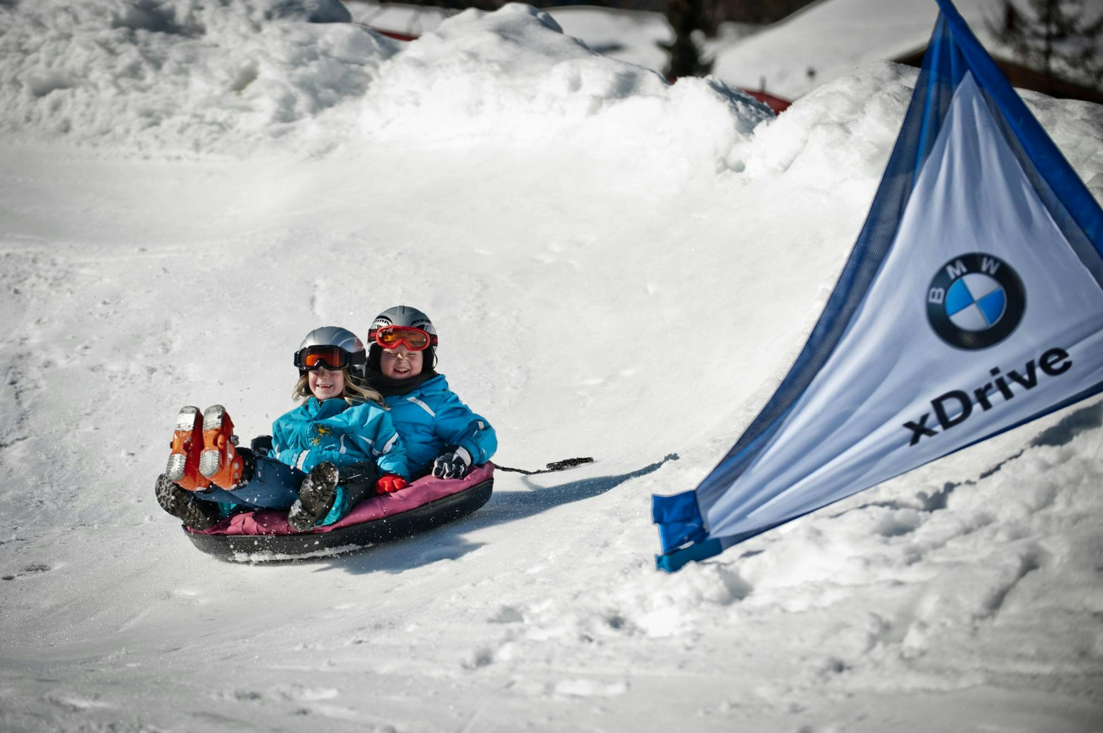 Snow Tubing: Kinder fahren im Schlitten in der Bodmi Arena Grindelwald im Winter.