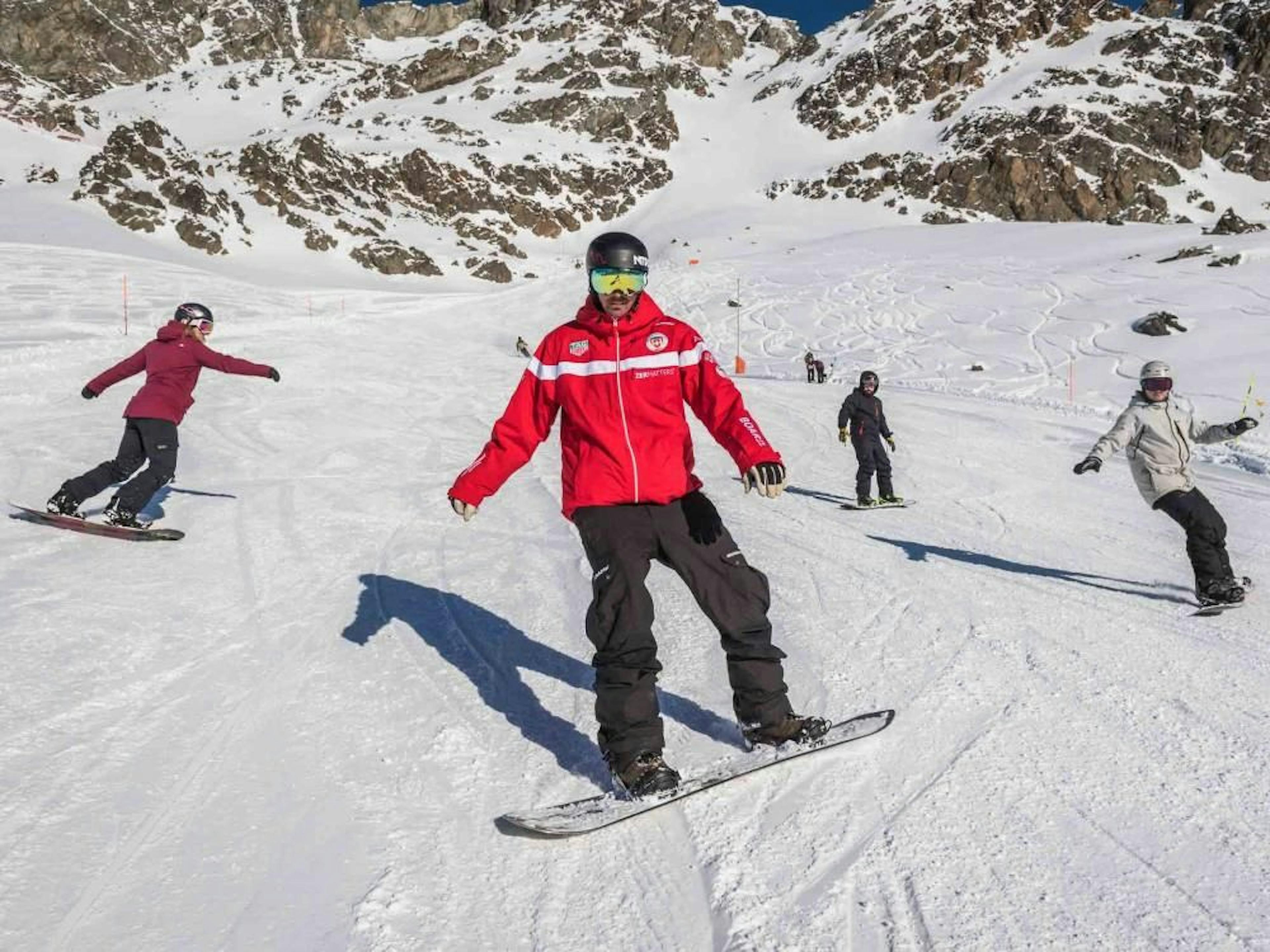 Curso de snowboard en Zermatt con participantes activos en la pista.