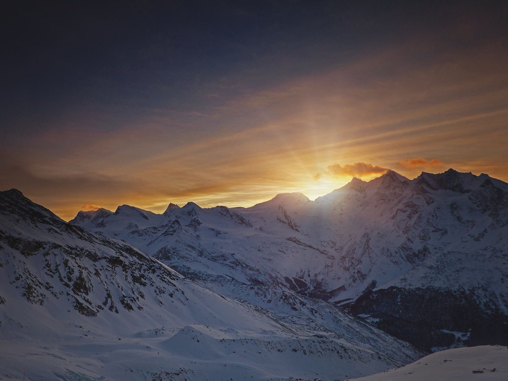 Saas Fee Nachtschlitteln mit schneebedeckten Bergen im Abendlicht.
