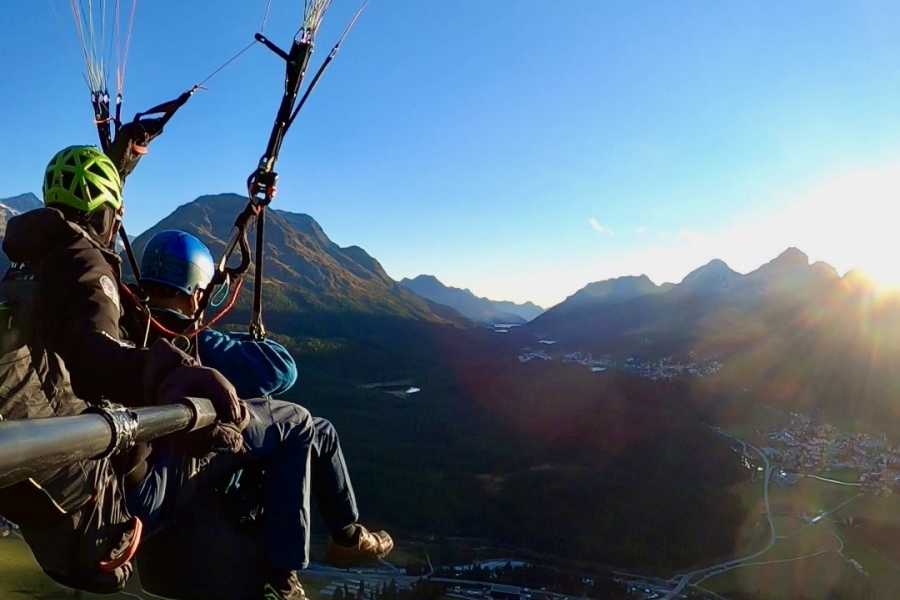 Sonnenuntergang beim Paragliding in Samedan: Erlebe den Tandemflug über die beeindruckende Berglandschaft.