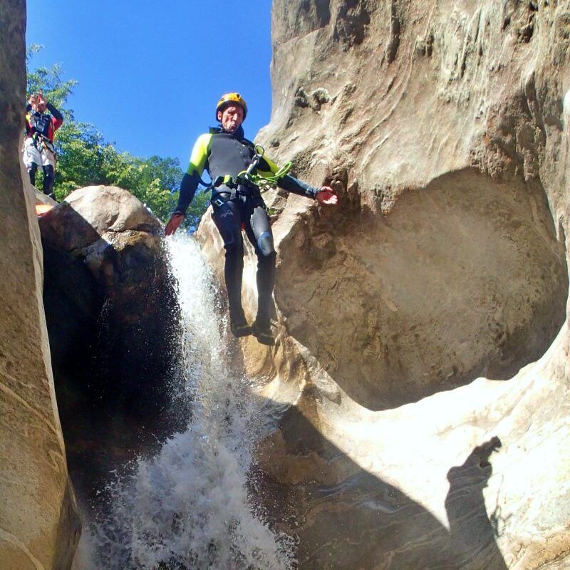 Lodrino canyoning: Osoba skáče do vody, skal, modrá obloha