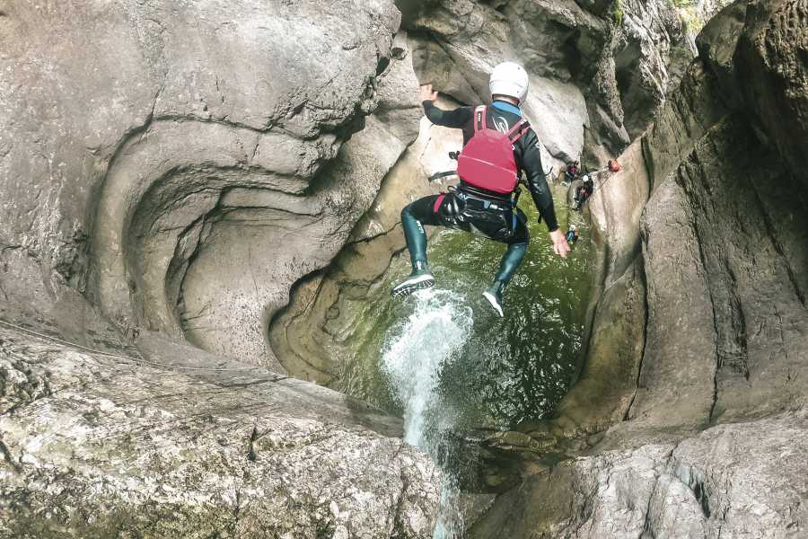 Sprung in die Chli Schliere Schlucht, Teilnehmer trägt Neoprenanzug, felsige Umgebung
