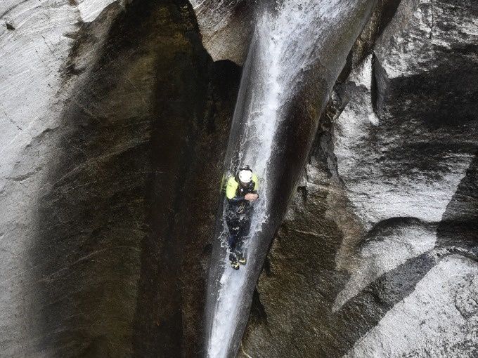Sprung Iragna Canyoning Expert na garganta, vestido à prova de água, desce a cascata.