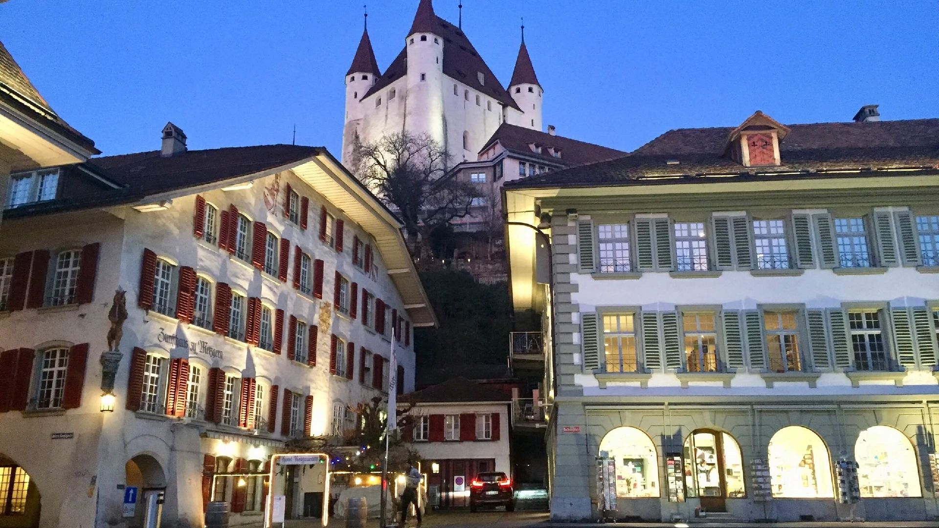 Kasteel Thun met omringende historische huizen bij nacht.