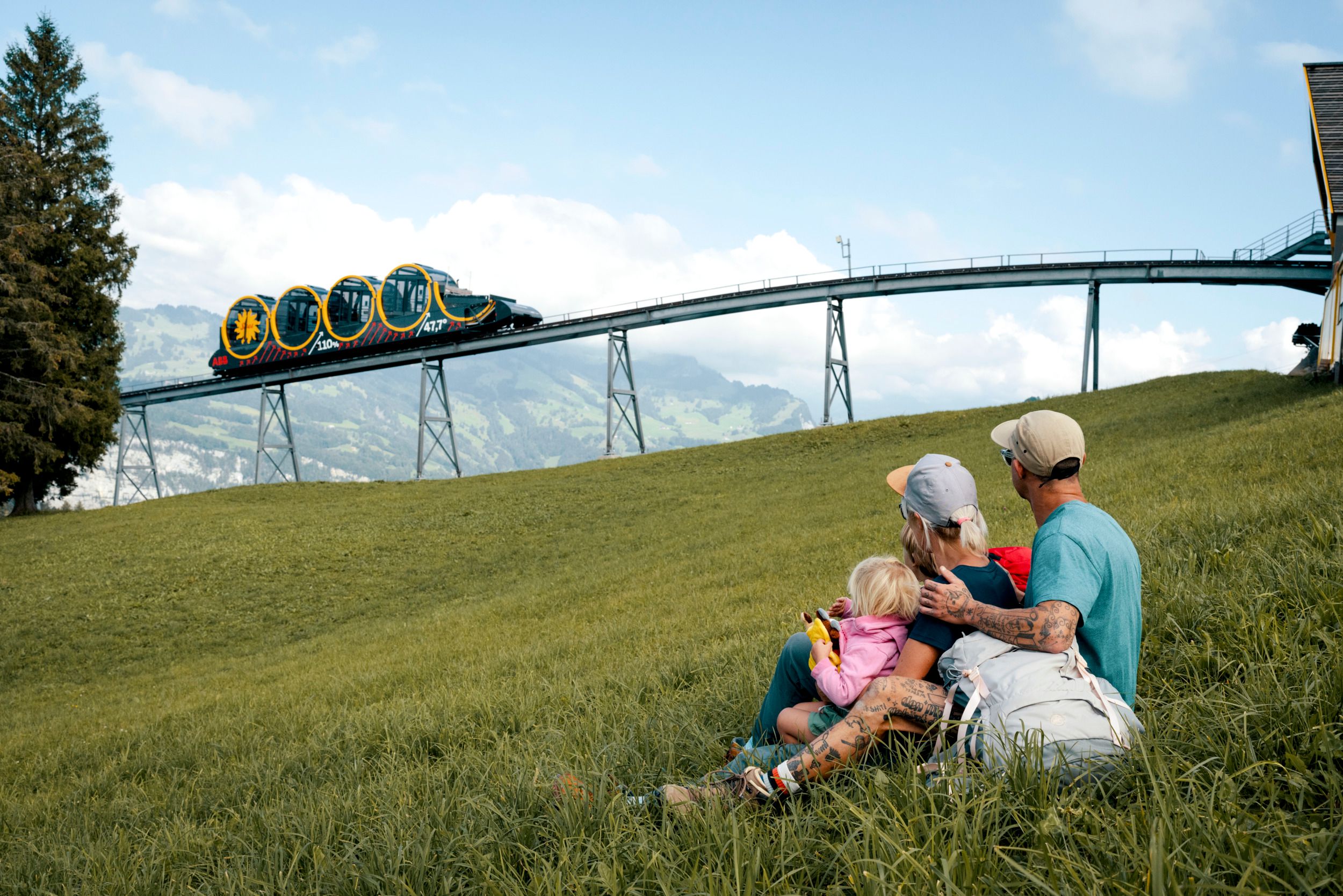 Stesen Puncak Stoos: Keluarga sedang bersantai, aktiviti musim panas dan pemandangan kereta api gunung.