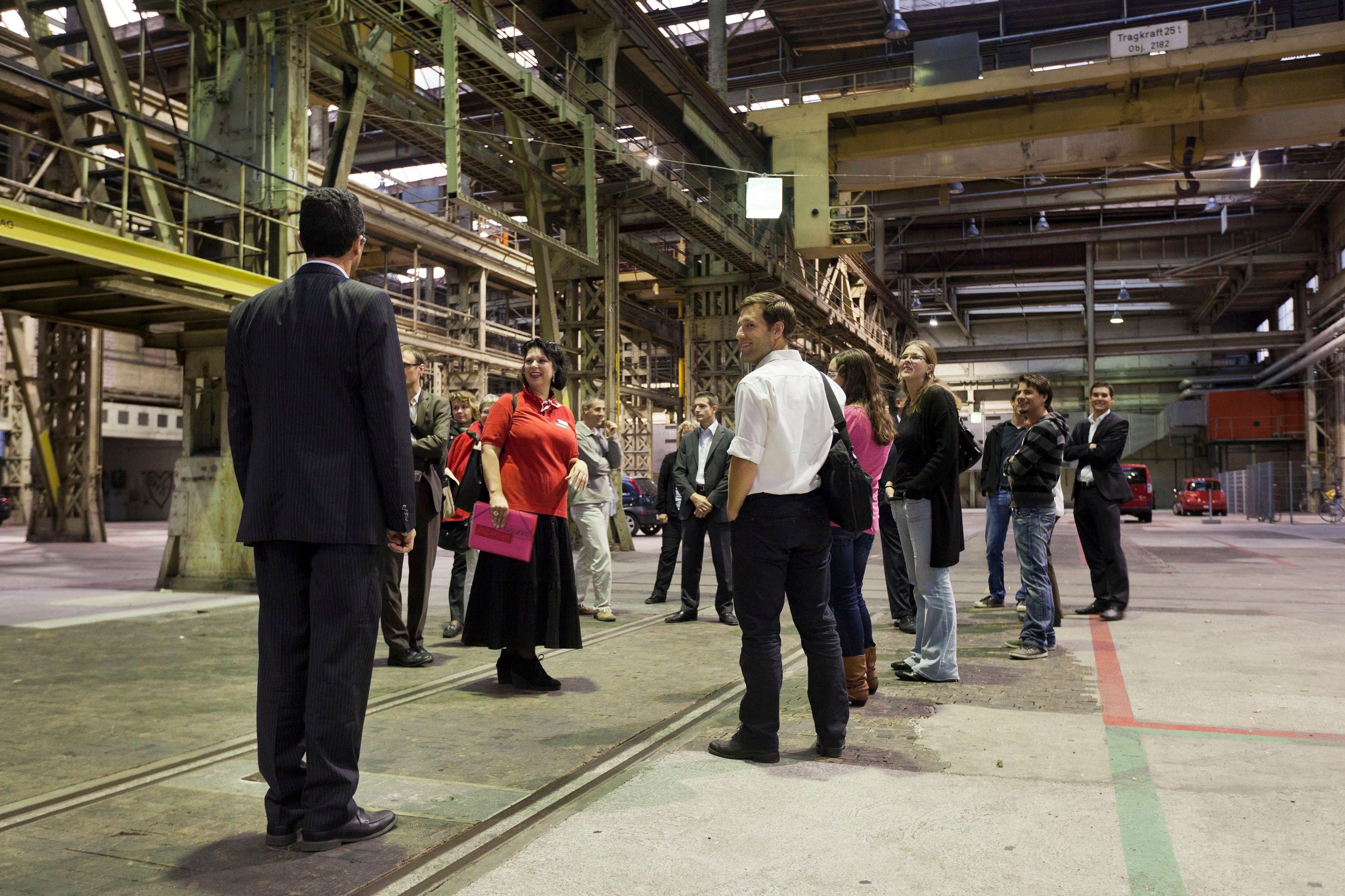 Prohlídka v areálu Sulzer s účastníky v pracovním oblečení, pohled na továrnu