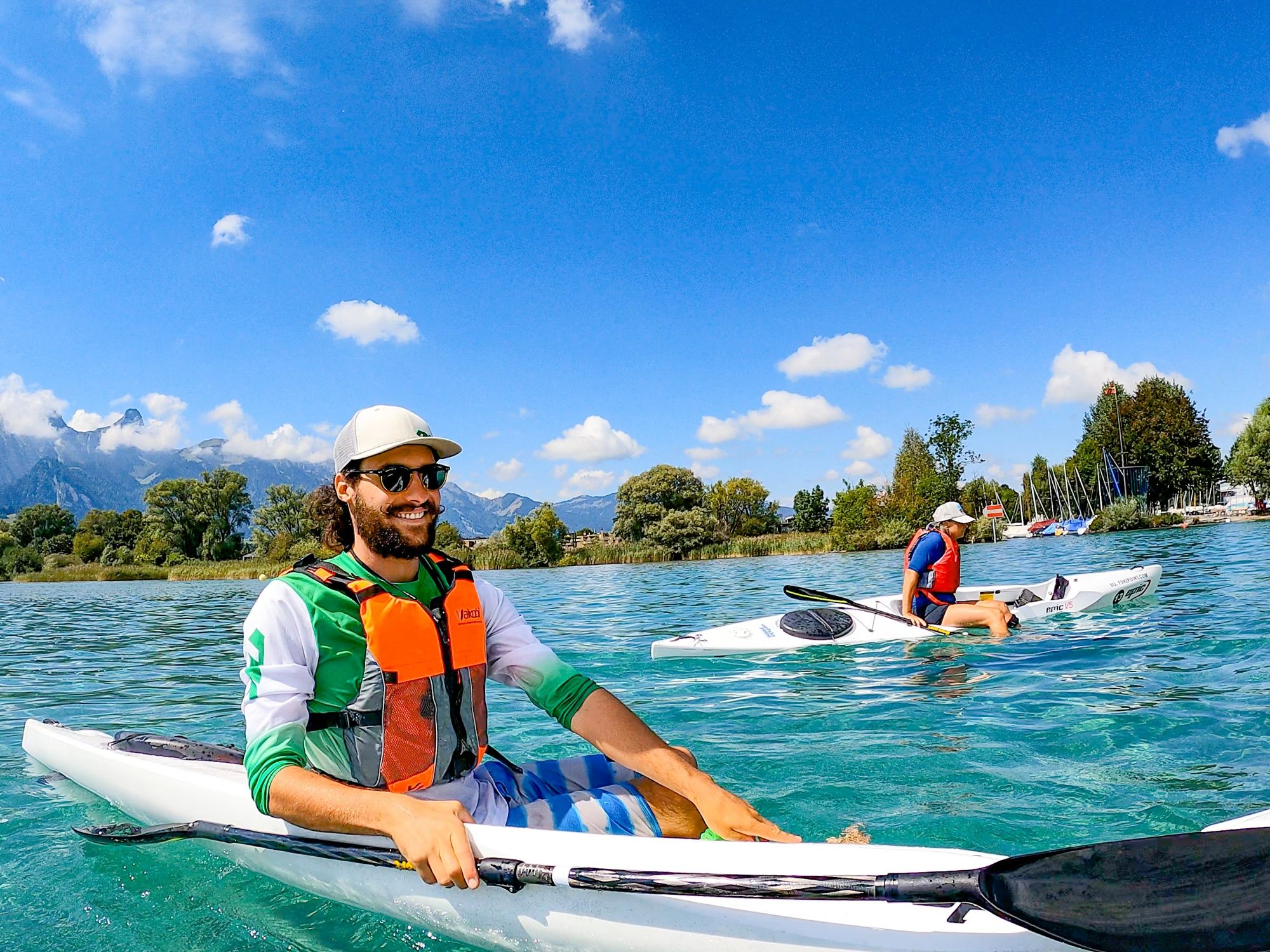 Surfskipoint: Relaxed kayaking on clear water with mountain views in summer.