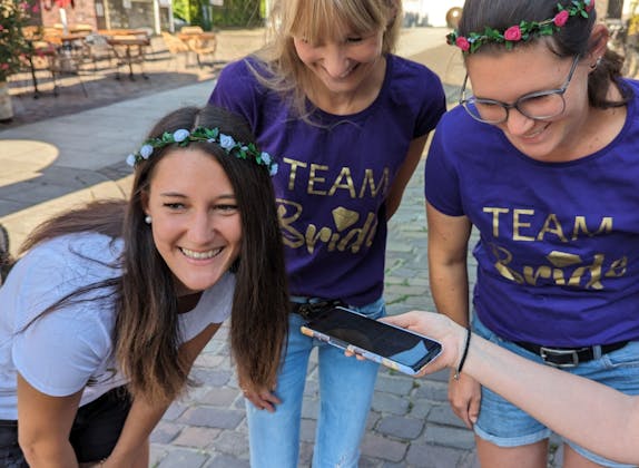 Beat the Braut: Drei Frauen lachen zusammen und genießen das Junggesellinnenabschied-Abenteuer in der Stadt.