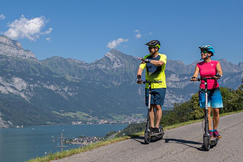 Elektroroller-Fahrer in der Schweiz rollen entlang der Berge.