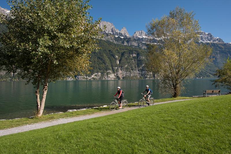 瓦伦湖的骑自行车的人在背景的山脉旁的车道上。