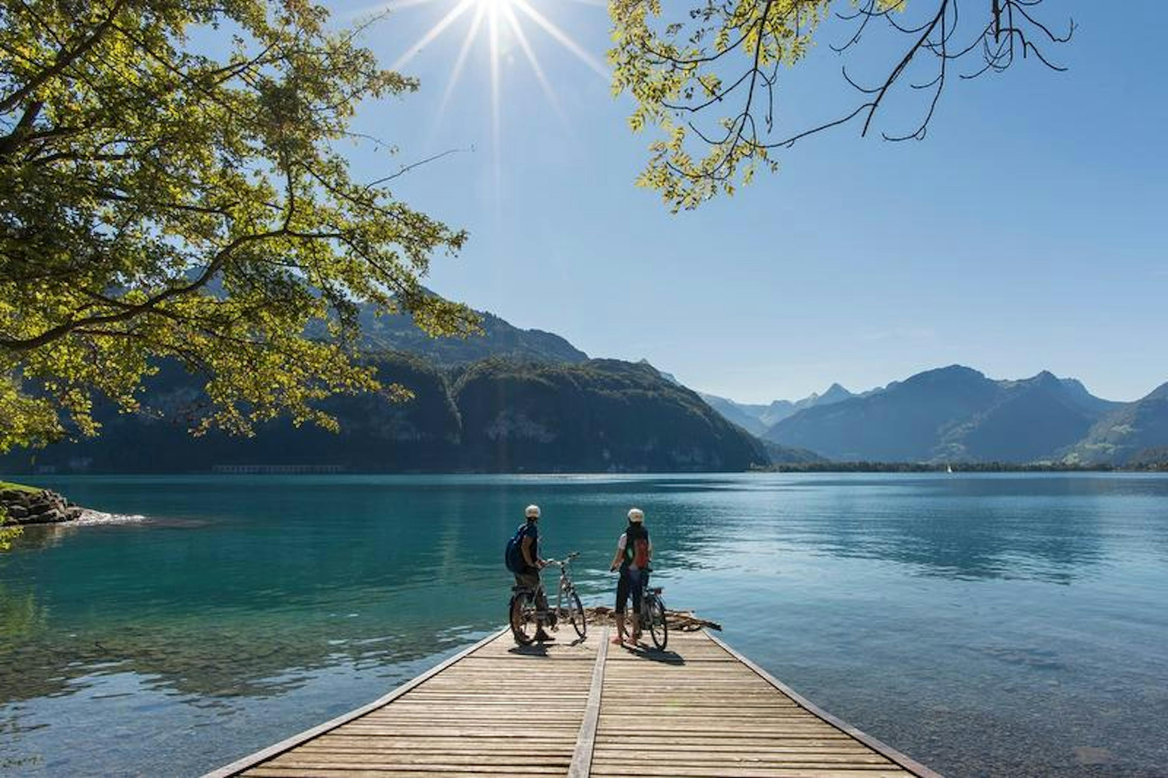 Walensee mit Radfahrern auf Holzsteg im Sonnenlicht