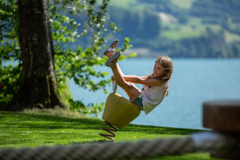 De speelervaring Walensee toont een kind op een wippertje buiten. Het is zomers en gelegen aan het Walensee.