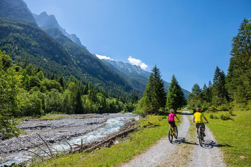 E-Bike-Tour in der Tamina Therme mit grüner Umgebung und Sonne.