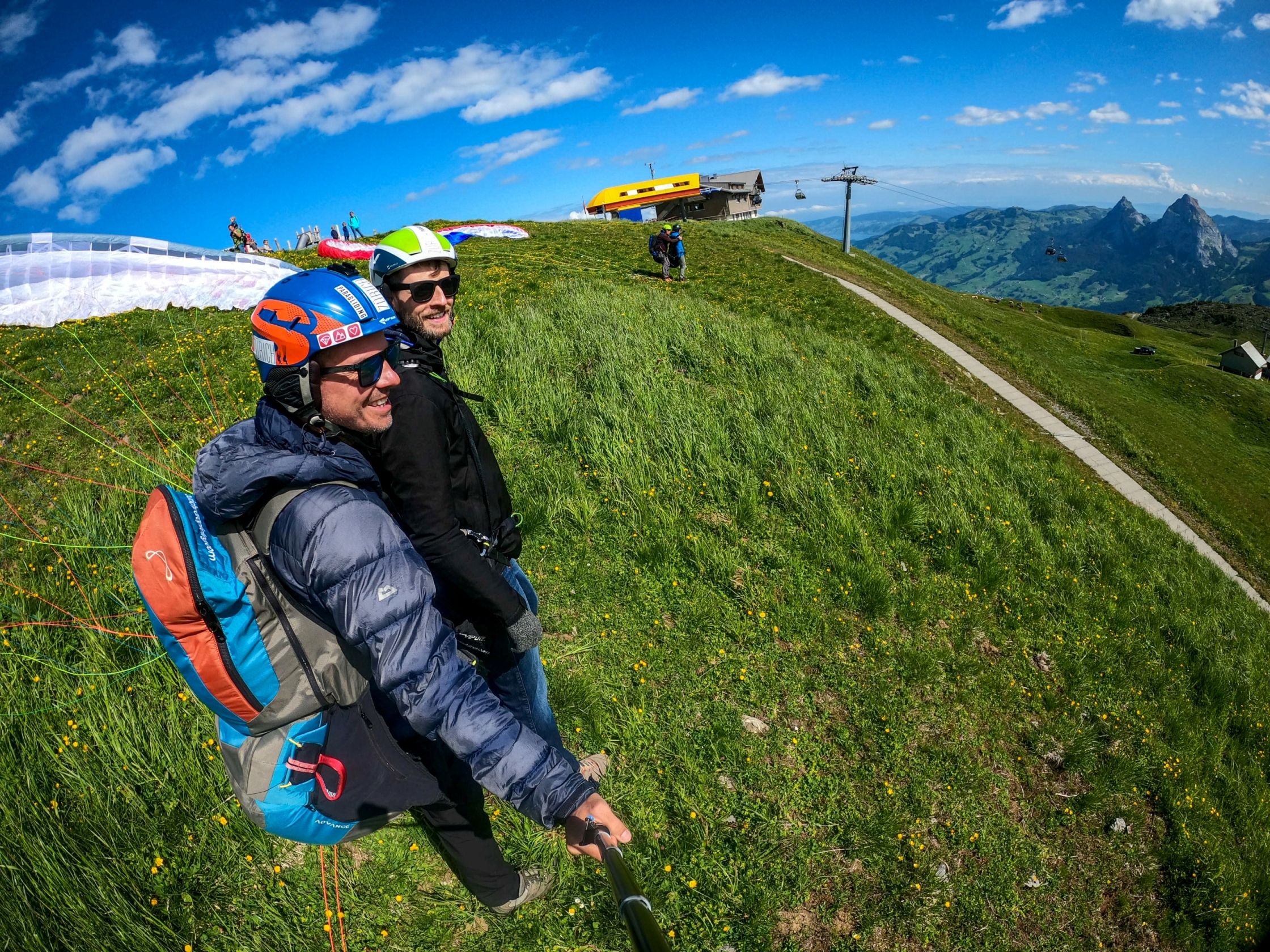 Parapente à Zurich avec vue sur les montagnes et les prairies.