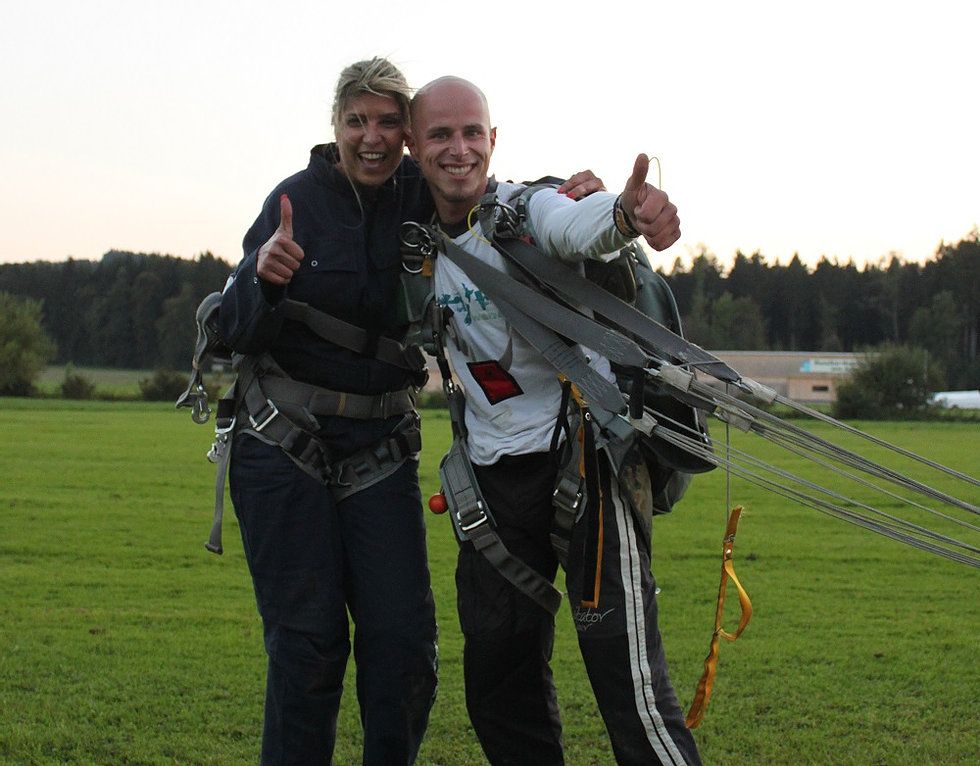 Lompat payung di Lucerne dengan dua penerjun, kebahagiaan setelah lompatan, hamparan hijau, cahaya sore.