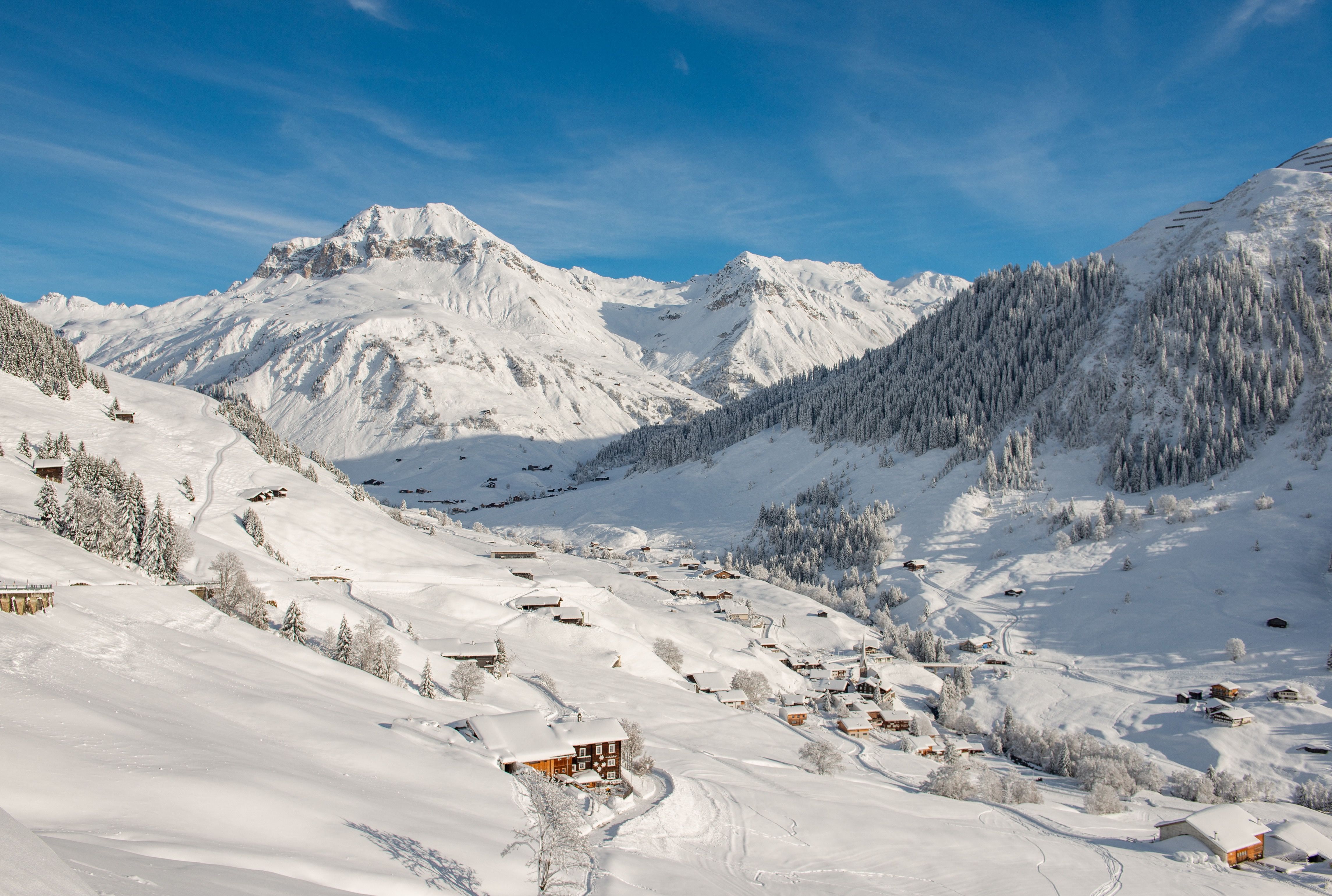 St. Antönien: Winter landscape with snow-covered mountains and charming huts in Prättigau.