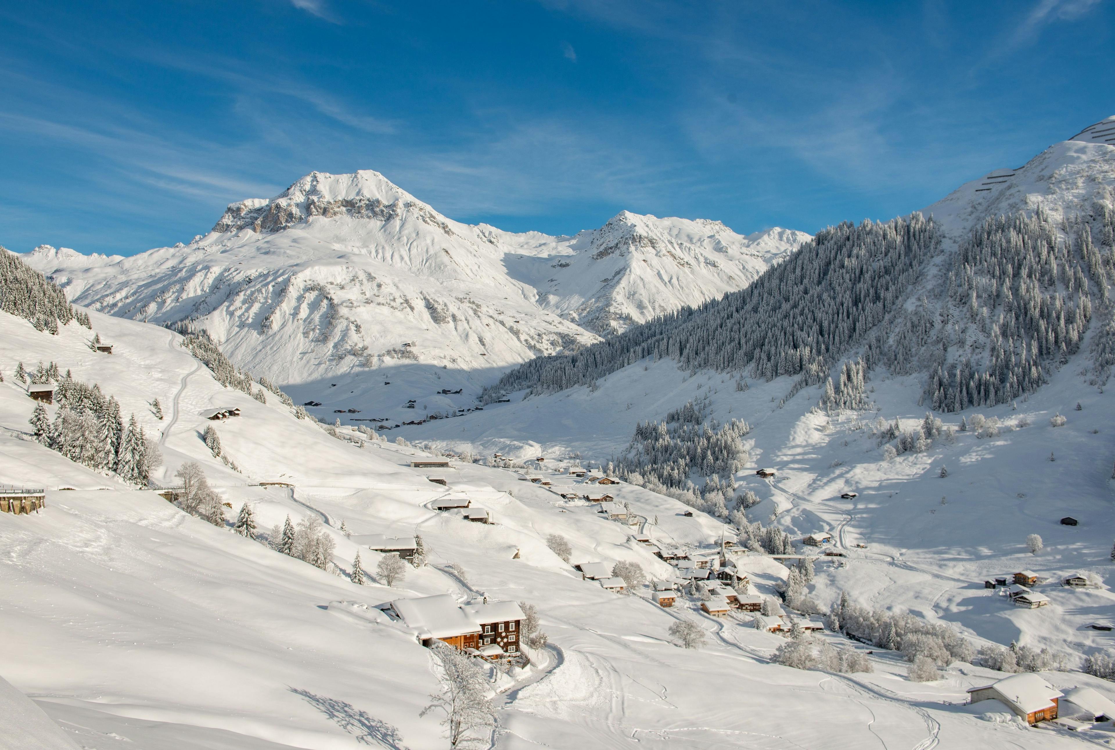 St. Antönien: Winterlandschaft mit schneebedeckten Bergen und charmanten Hütten im Prättigau.