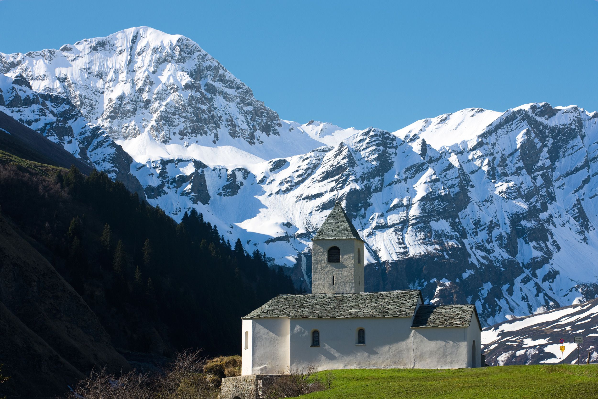 Thalkirch Safien : vue sur l'église enneigée avec des montagnes majestueuses en arrière-plan.
