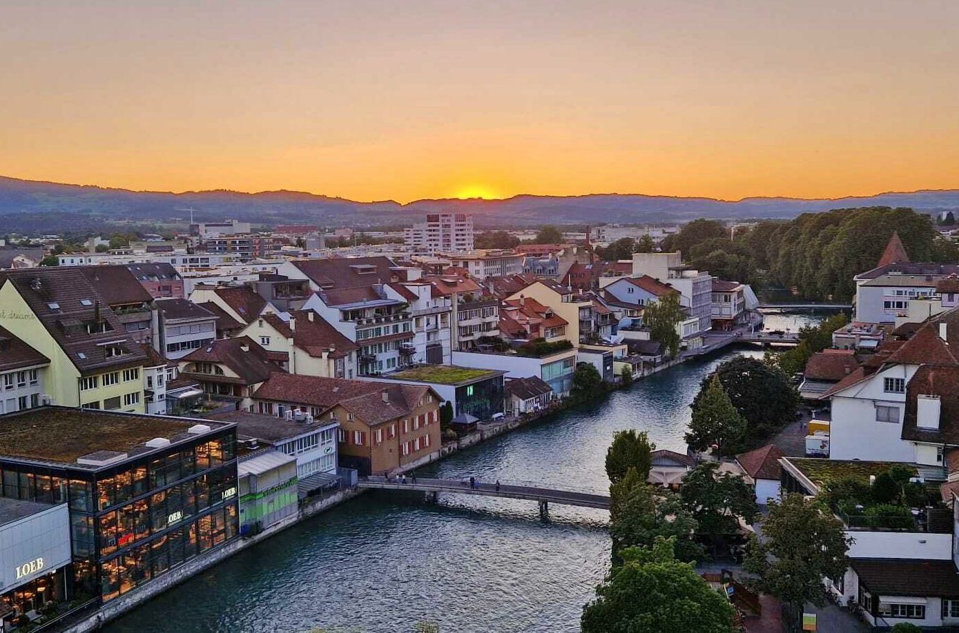 Thun: impresionante atardecer sobre la ciudad al borde del río Aare con vista a las montañas.
