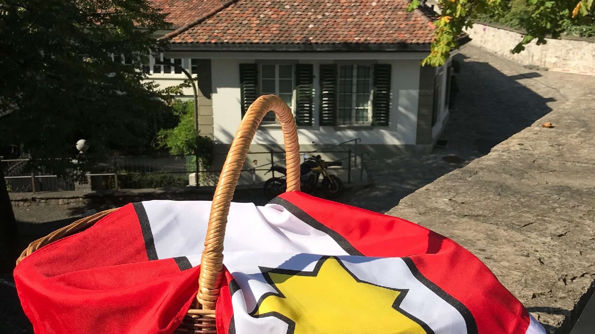 Keranjang cerita tadika di Thun dengan bendera dan pemandangan bangunan.