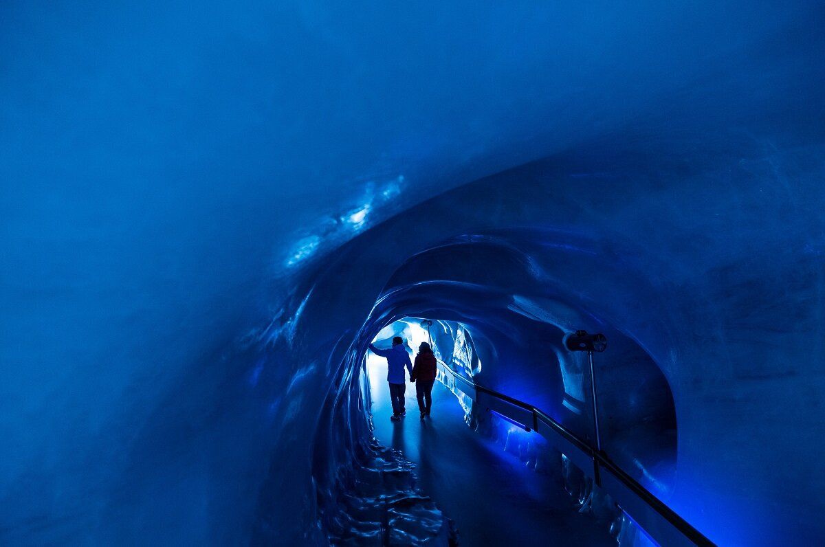 Titlis Gletscherhöhle mit eisblauem Licht und Besuchern.