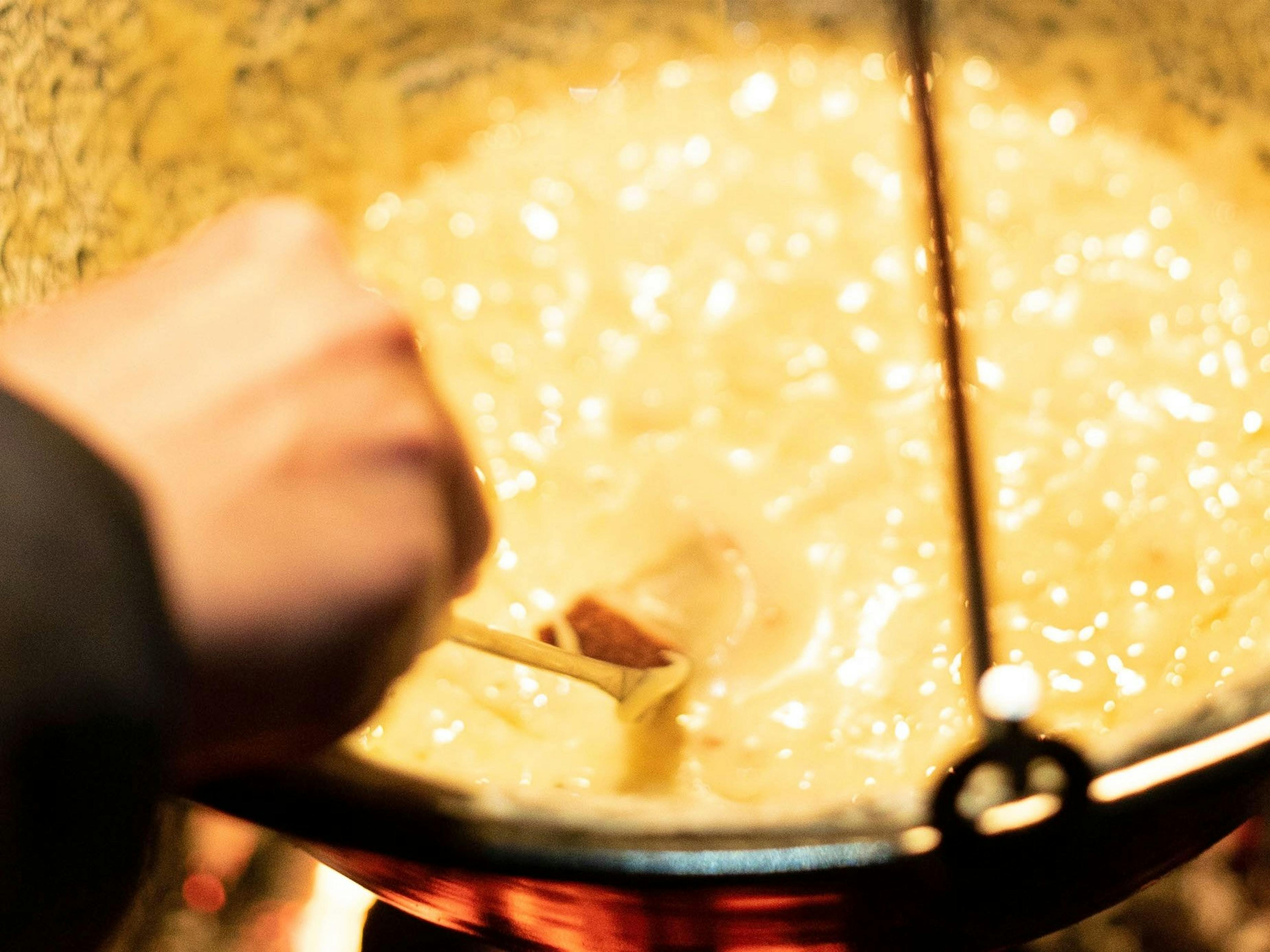Fondue Essen in Zermatt, hand rührt Käse im Topf