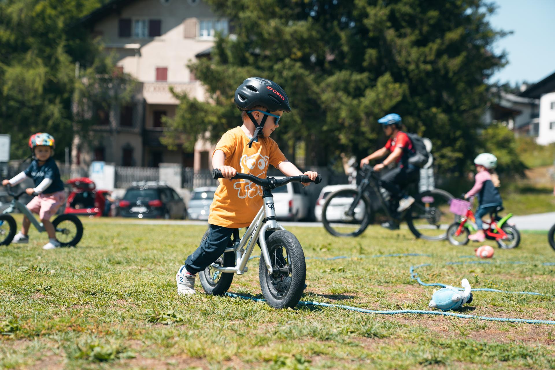 Murmeltier league: Kinder auf Bikes im Sommer in der Natur, spielend mit viel Freude.