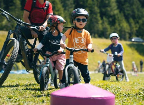Liga marmotei: Copii pedalează vara în natură, înconjurați de munți spectaculoși.
