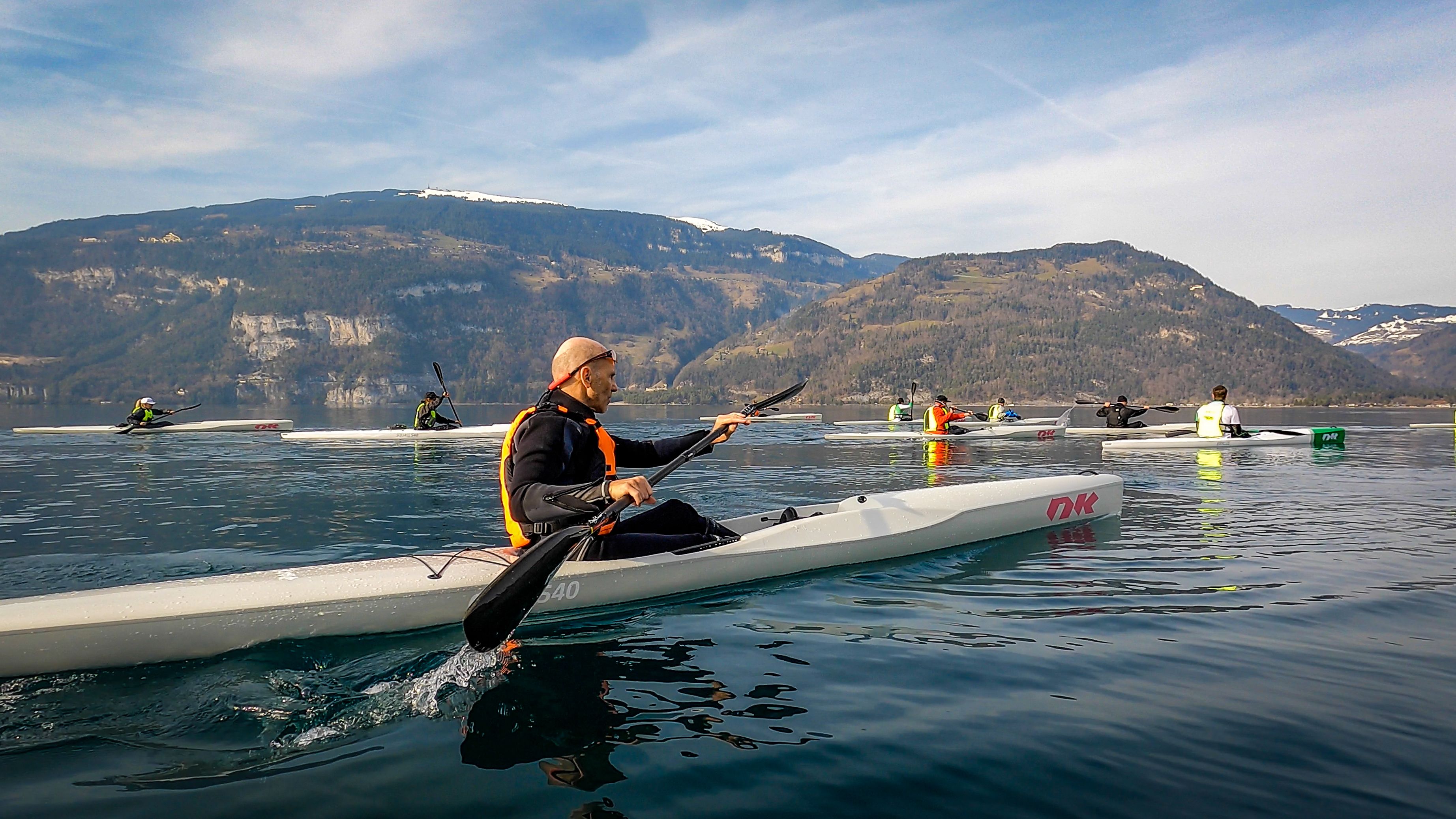 水上でパドリングしているサーフスキーカヤック、静かな環境、背景に山