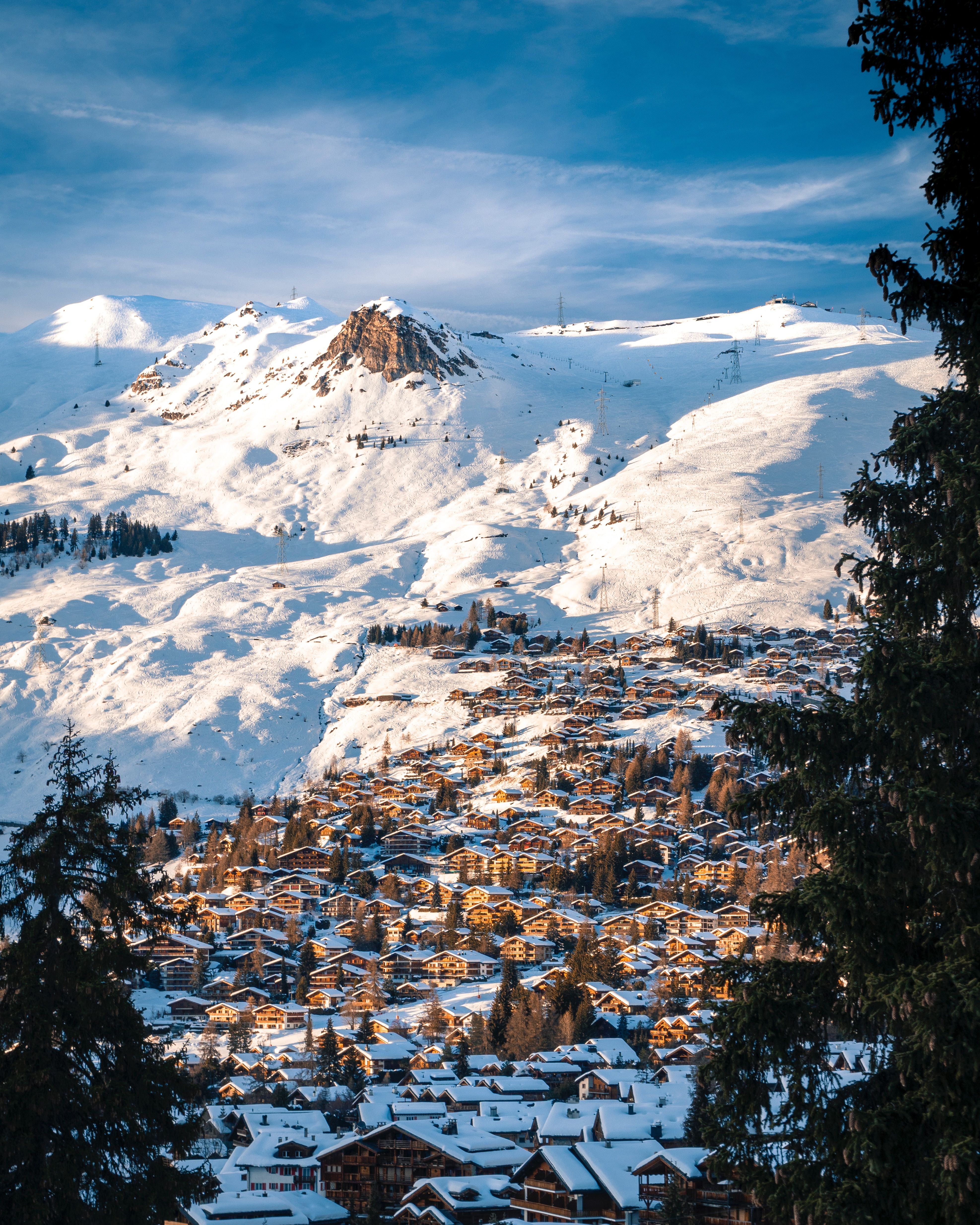 Verbier: Vinterskogsbild med snötäckta berg och idylliska châlets i Alperna.