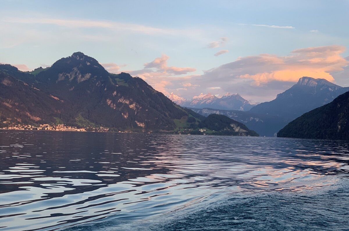 Vierwaldstättersee mit ruhiger Wasseroberfläche, Bergen und Wolken im Hintergrund.