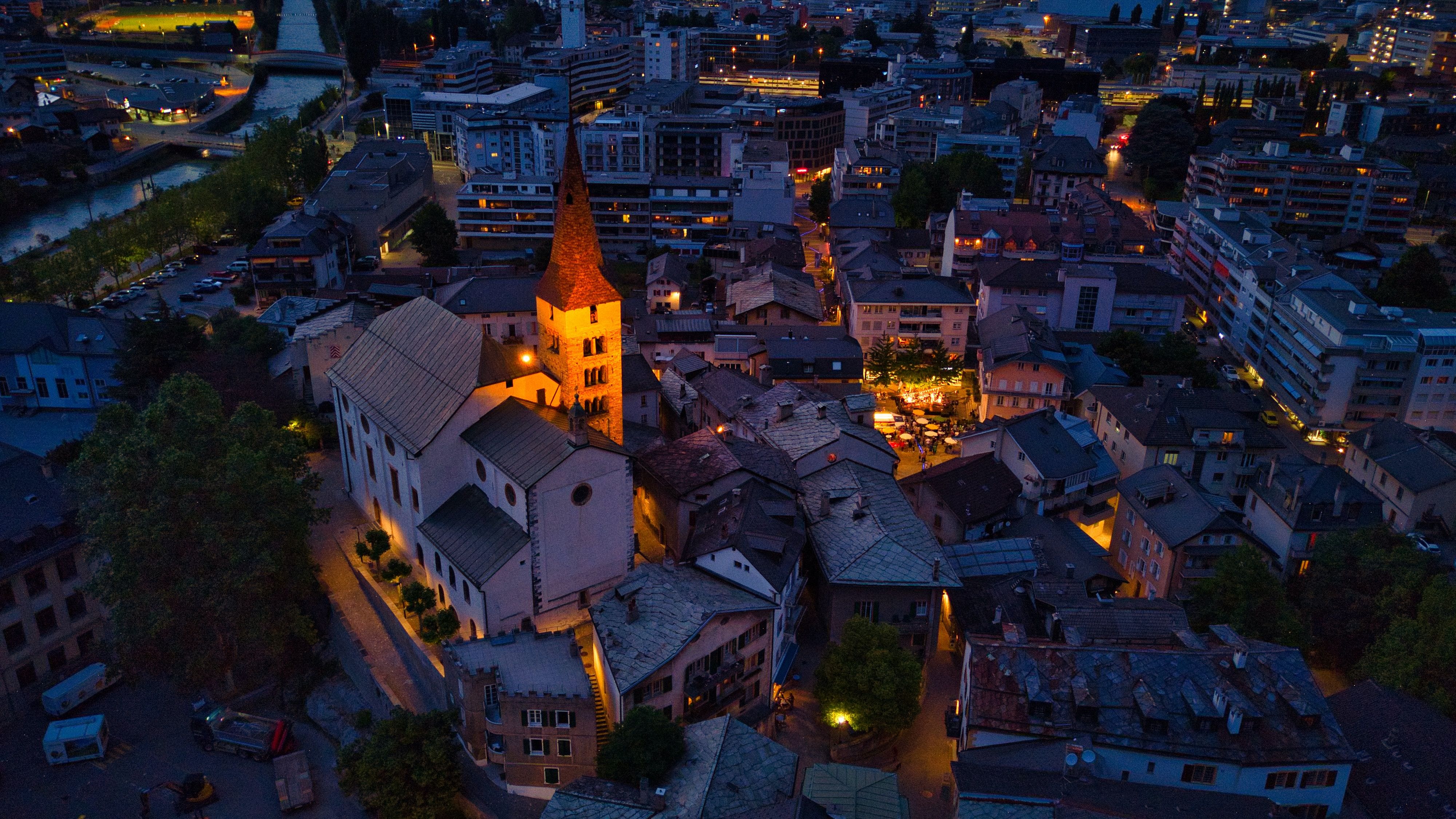 Visp: encantadora vista nocturna de la ciudad con casas iluminadas y el histórico edificio de la iglesia.
