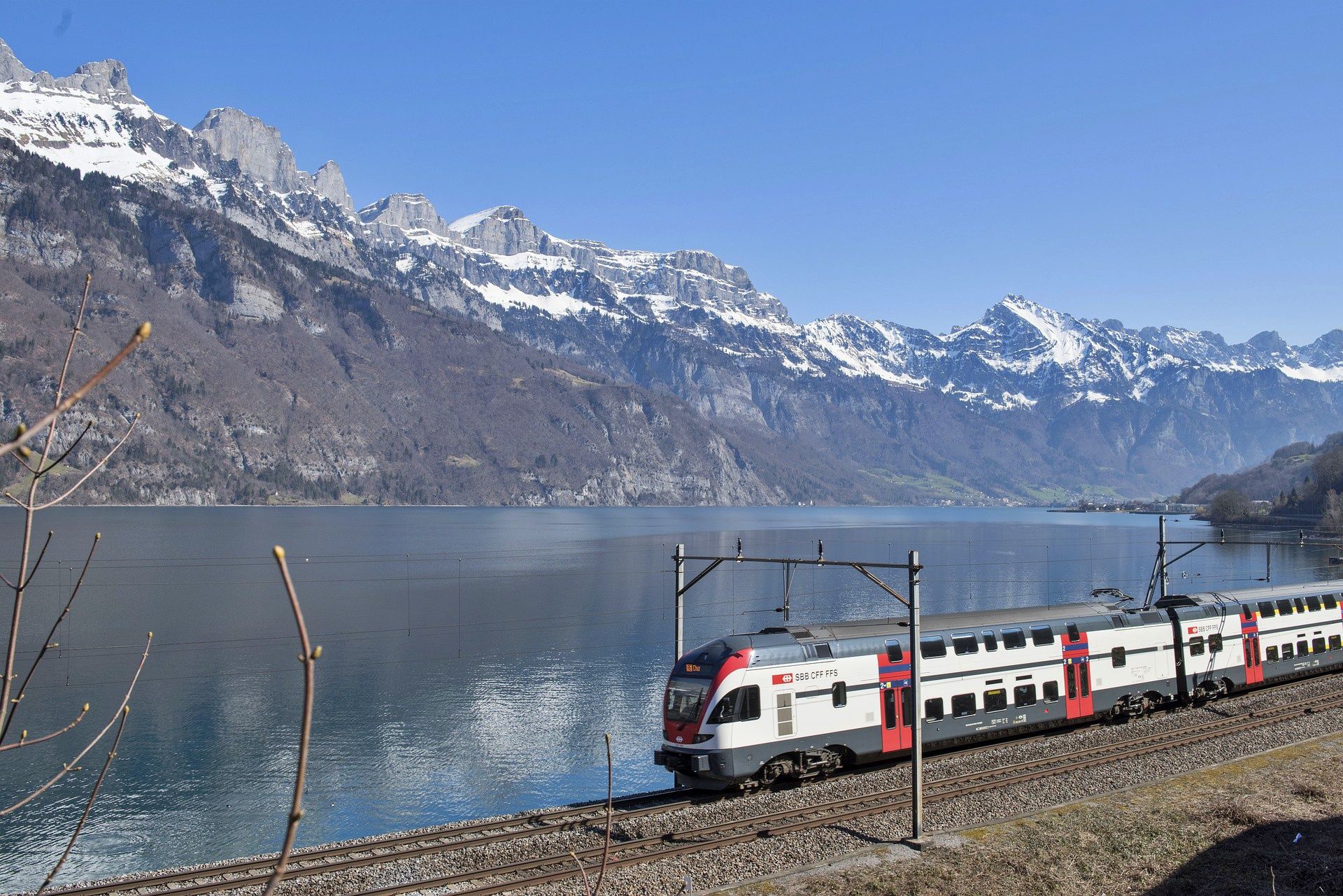 Walensee: Perjalanan kereta di Walensee dengan latar belakang pegunungan yang mengesankan dan langit cerah.