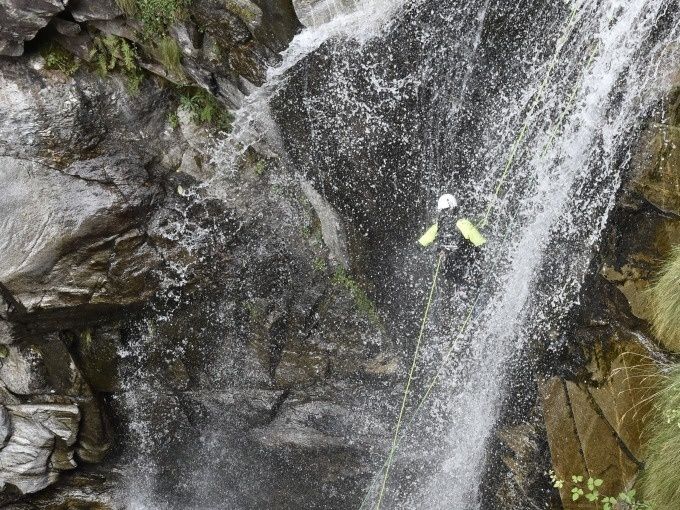 Cascata Iragna com especialistas em canyoning a descer de rappel. Muita água e rochas visíveis.