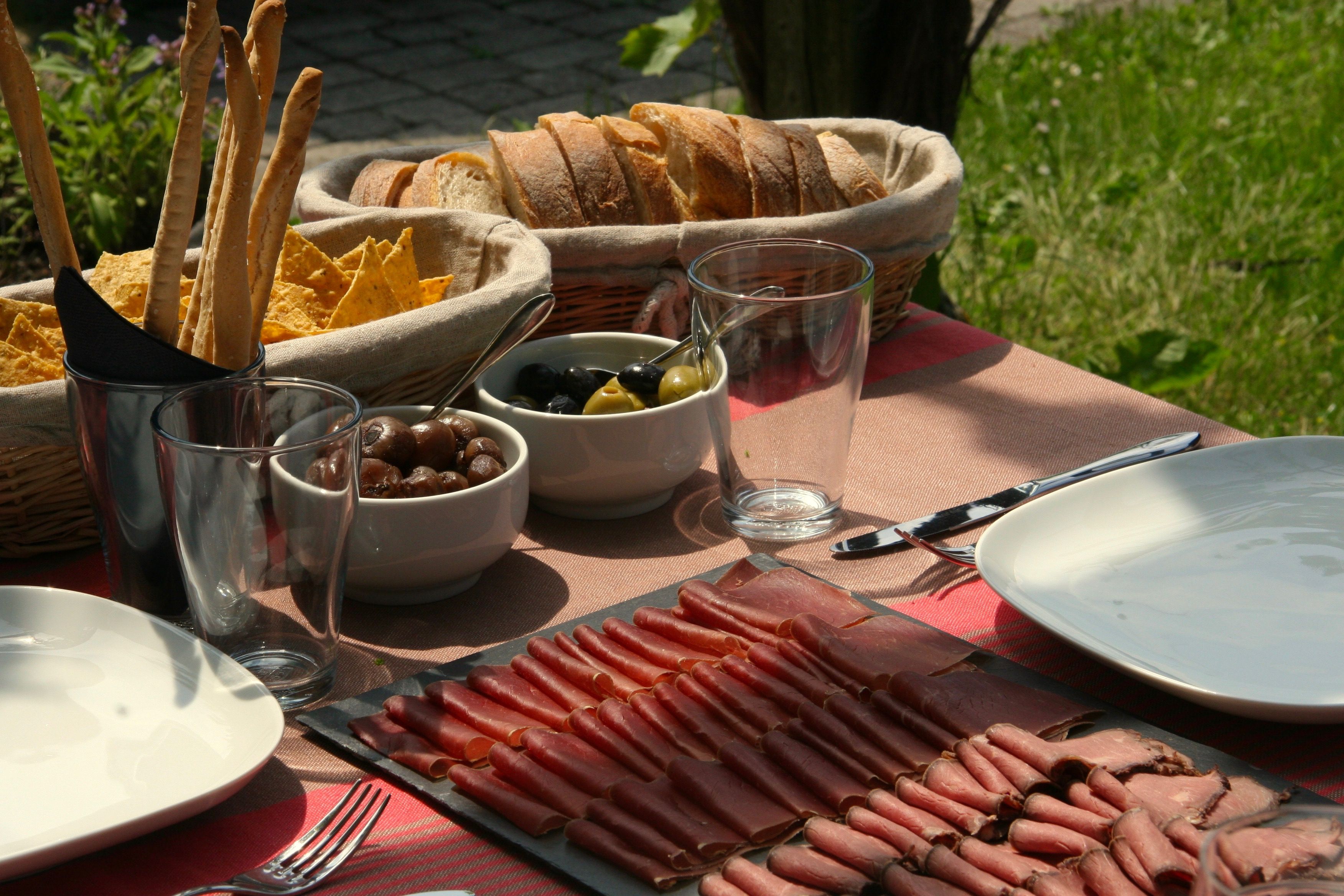 Tour di vini con specialità grigionesi, salsiccia e pane sul tavolo all'aperto