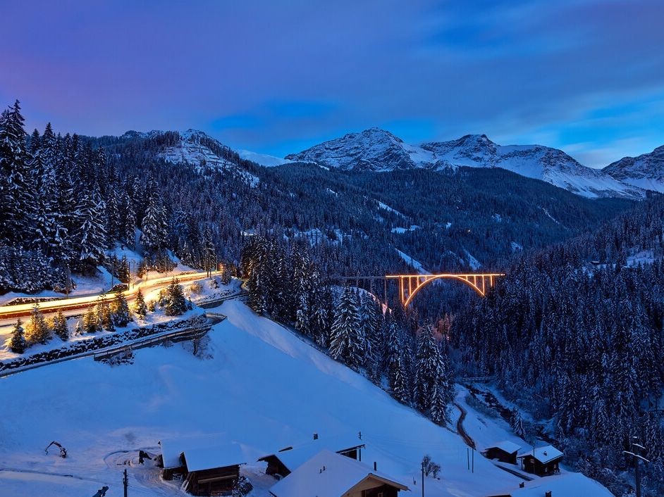 قطار وينتر أروزا تحت الثلج، جسر مضاء، منظر طبيعي شتوي.