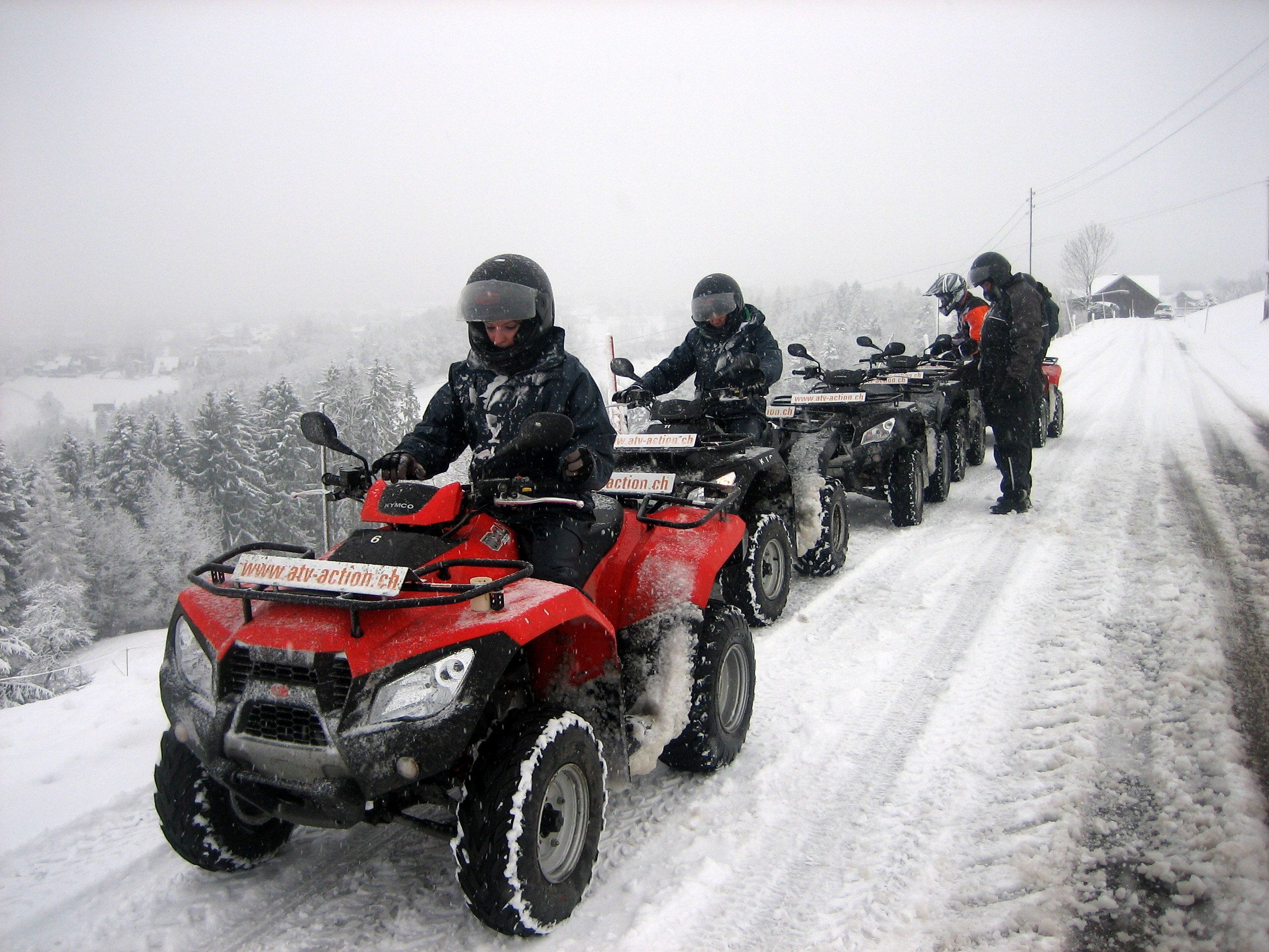Квадроциклы на снежной местности с водителями на квадроциклах