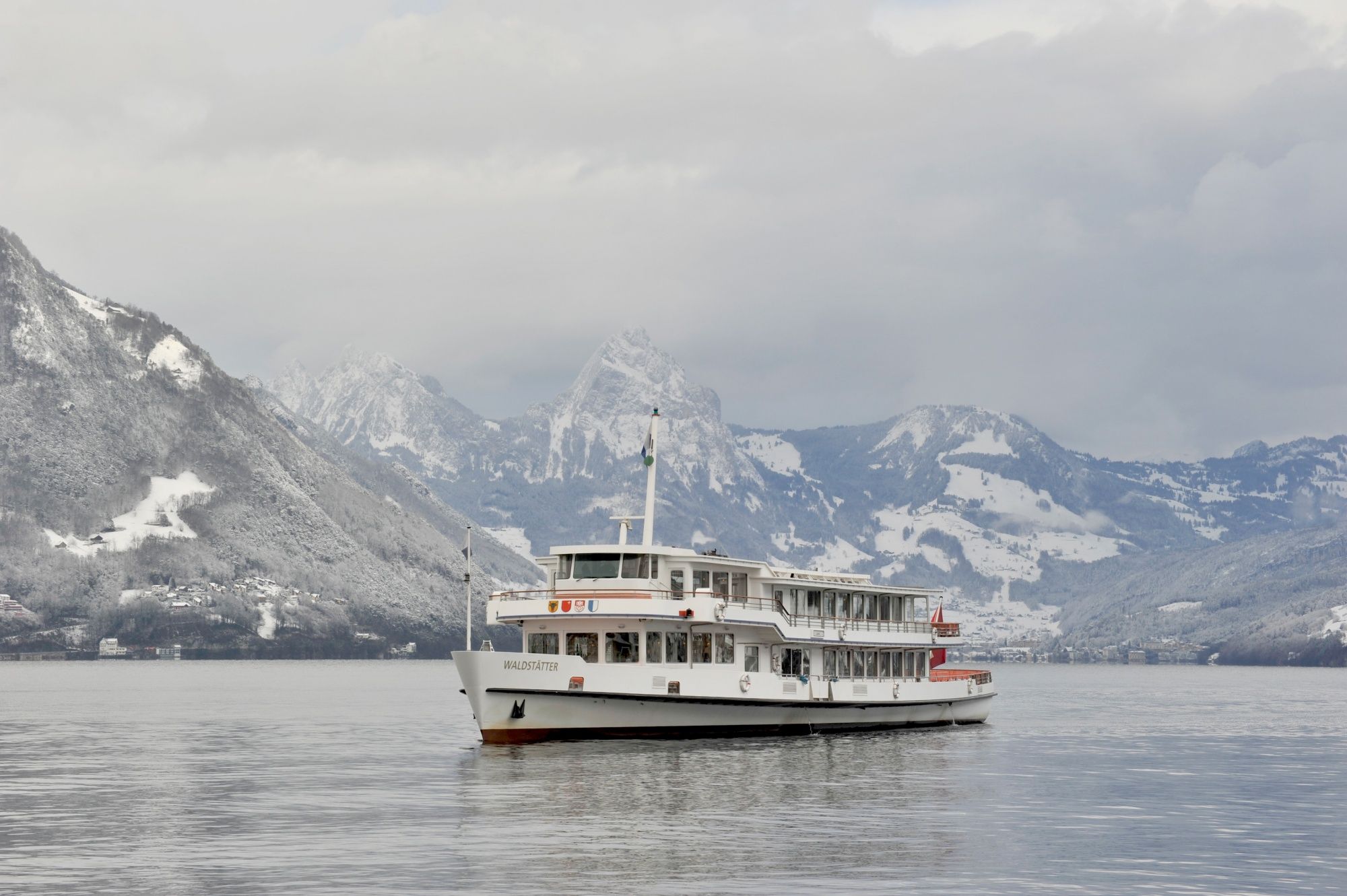 Vinter vid Vierwaldstättersee: Färgglatt fartyg på sjön framför snötäckta berg i vinterlandskapet.