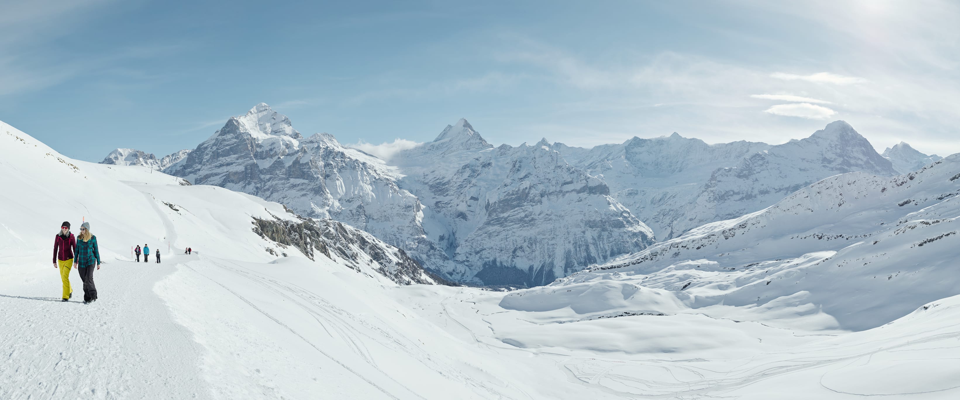 Winterwandern in Grindelwald First mit verschneiten Bergen und klarem Himmel.