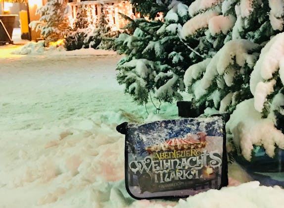 Weihnachtsmarkt: Schneebedeckter Boden und festliche Stimmung mit Lichtern und Verkaufsständen.